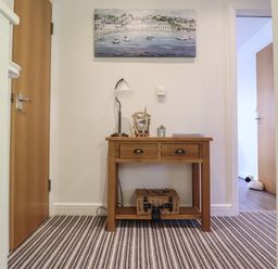A wooden table with drawers and decorative items on top between two wooden doors at Harbour View in Porthmadog