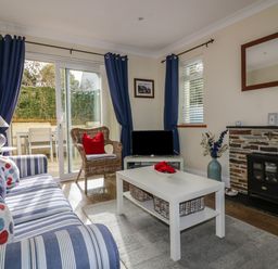 A living room with striped sofa or blue curtains and fireplace at Hazel Cottage in Tintagel