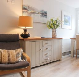 A living room with a chair, lamp, and cabinet at Simples in Dartmouth