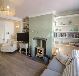 A living room with a fireplace and bookshelves at Heath Cottage in Stratford-Upon-Avon