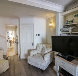 A living room with an armchair and TV stand at Heath Cottage in Stratford-Upon-Avon