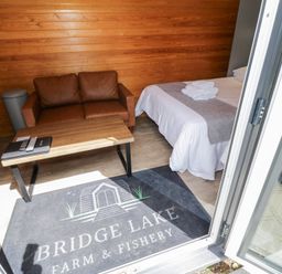 A room with a bed and a sofa at Willow Lodge At Bridge Lake Farm & Fishery Chacombe