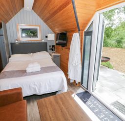 A bedroom with a bed and chairs at Willow Lodge At Bridge Lake Farm & Fishery in Chacombe