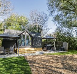 A cabin with a terrace and outdoor seating at Willow Lodge At Bridge Lake Farm & Fishery, Chacombe
