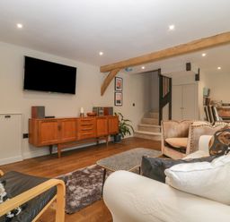 A living room with wooden cabinet and wall mounted TV at The Courtyard - Hilltop Barn Winterborne Zelston near Wareham