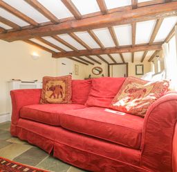A red sofa with patterned cushions and wooden beam ceiling at Field View in Curland near Taunton