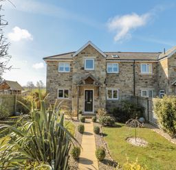 A stone house with a front garden and a paved path leading to the door at Cushat House Stamford near Embleton