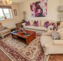 A living room with armchairs and a sofa around a wooden coffee table at Cushat House Stamford near Embleton