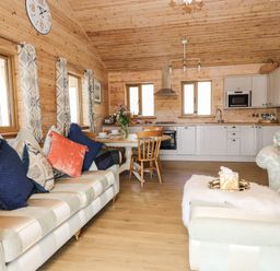 A living area with sofas cushions a dining table and kitchen cabinets at The Larches Van near Llanidloes