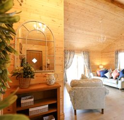 A living room with wooden walls curtains sofas and a round dining table at The Larches in Van near Llanidloes