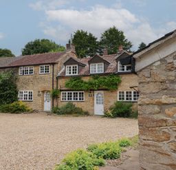 An outdoor view of a cottage with stone walls and gravel at The Old Bakery South Perrott near Mosterton