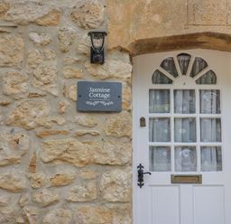 The exterior wall with a door and sign at Jasmine Cottage South Perrott near Mosterton