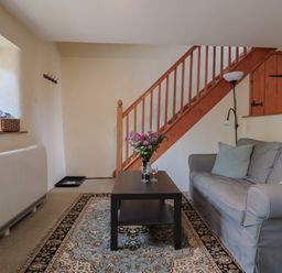 A living room with a sofa, coffee table, and staircase at Jasmine Cottage, South Perrott near Mosterton