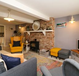 A living room with yellow and gray chairs a brick fireplace and a television at Harbour Reach Brewers Quay Harbour