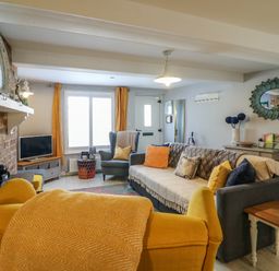 A living room with a yellow armchair sofa and television at Harbour Reach Brewers Quay Harbour