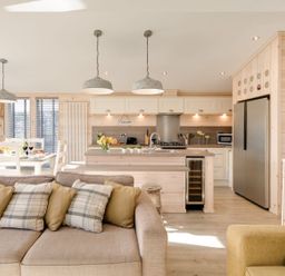 An open plan kitchen and dining area with a sofa and armchair in a wooden interior at Lobster Lodge Runswick Bay