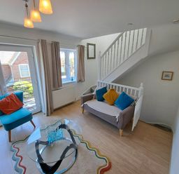 A living room with a sofa and armchair near a staircase at Castle Cove View in Castle Cove