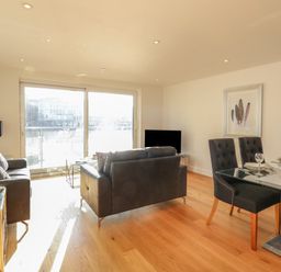 A living room with black sofas glass dining table and sliding doors at Harbourside Haven Apartment 2 in Weymouth