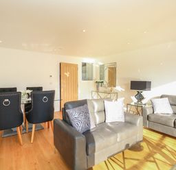 A living room with two gray sofas and a dining table with black chairs at Harbourside Haven Apartment 2 in Weymouth