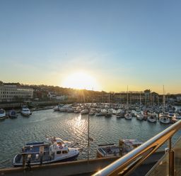 A marina with boats docked and buildings in the background at sunset at Harbourside Haven Penthouse 1 in Weymouth