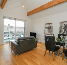 A living room with black leather sofas and a glass dining table with black chairs at Harbourside Haven Penthouse 2 in Weymouth