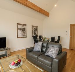 A living room with a leather sofa glass coffee table and dining table with chairs at Harbourside Haven Penthouse 2 in Weymouth