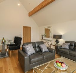 A living room with leather sofas glass coffee table and dining table with chairs at Harbourside Haven Penthouse 2 in Weymouth