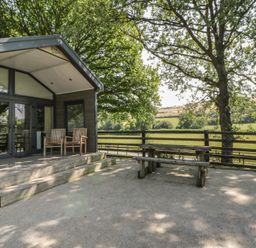 An outdoor area with wooden chairs and a table at Woodland Escape in Rhayader