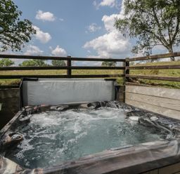A hot tub with water and a fence at Woodland Escape in Rhayader