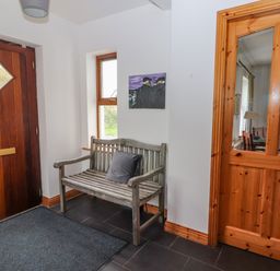 An entryway with a wooden bench and cushion near a wooden door and glass-paneled wooden door at Cherry Blossom Cottage Quilty County Clare