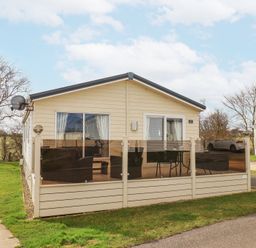 An exterior view of a single-story mobile home with a patio and outdoor furniture at Two Little Ducks in Cayton