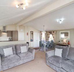 An open living area with two grey sofas a dining table and chairs a kitchen with cabinets and appliances at Two Little Ducks in Cayton