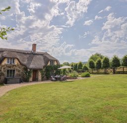 A garden with a thatched house outdoor furniture and trees at Garden View in Wellington