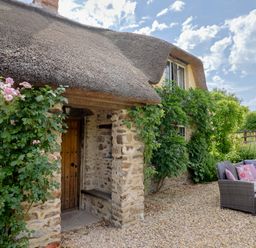 A cottage with a thatched roof and stone walls at Garden View in Wellington
