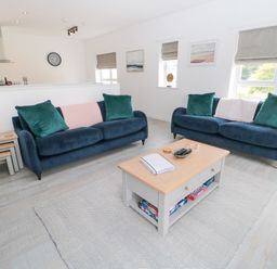 A living room with two blue sofas green pillows a wooden coffee table and wall art at Summer Rose in Craster