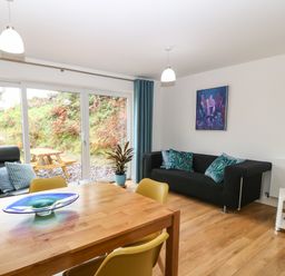 A dining table with yellow chairs and a living room with a black sofa and blue pillows at Hen Gapel in Waunfawr Gwynedd