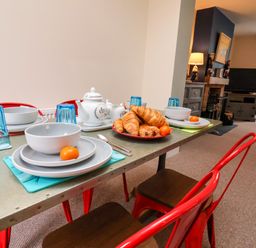 A dining table set with bowls plates croissants and blue glasses in a living room with a television and fireplace at Over Esk in Whitby