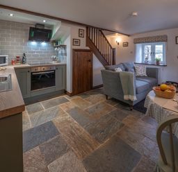 A kitchen and living area with a stove sofa and dining table at Crooks in Axbridge