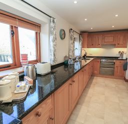 A kitchen with wooden cabinets black countertop a toaster kettle and canisters at Granary Cottage Blackwell near Ilmington