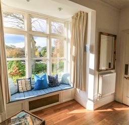 A window seat with blue cushions and pillows next to a radiator and a mirror at Victoria Lodge in Kingsbridge