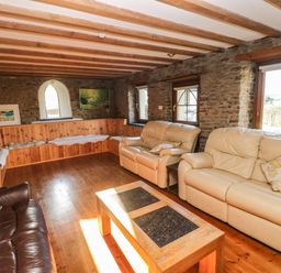 A living room with leather sofas wooden coffee table built in wooden bench and stone walls at Nant Moel Isaf Farm in Rhydyfro near Pontardawe