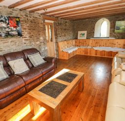 A living room with brown leather sofa beige sofa wooden corner bench and a wooden coffee table at Nant Moel Isaf Farm in Rhydyfro near Pontardawe
