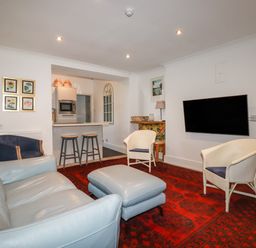 A living room with a sofa ottoman armchairs and wall mounted television at Melvill Lower Deck in Falmouth