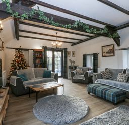 A living room featuring a sofa, armchairs, and a Christmas tree at Ty Gwennol in Llanfaethlu