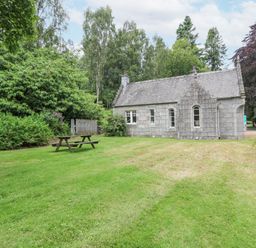 A stone cottage with a slate roof surrounded by grass and trees with a picnic bench outside at East Lodge - Crathes Castle in Crathes Castle near Banchory