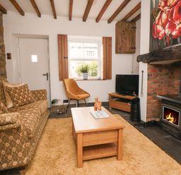 A living room with a patterned sofa wooden coffee table and a wood burning stove at Ascot Cottage Sheriff Hutton near Strensall