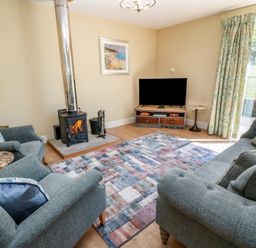 A living room with a wood stove and television at Ardlochan Lodge - Culzean Castle in Maybole