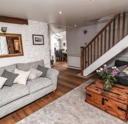 A living room with sofas a wooden chest as coffee table flowers on the table and a staircase at Garretts in Kingsand And Cawsand