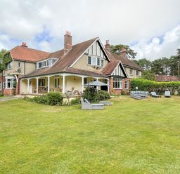 A large house with a covered porch and lawn furniture on the grass at Deer Leap House in Moreton