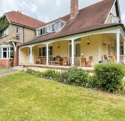 An outdoor patio with chairs tables and plants attached to a house with a sloped roof at Deer Leap House in Moreton